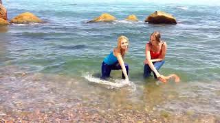 girls in wet clothes get wet in the sea and play in the water