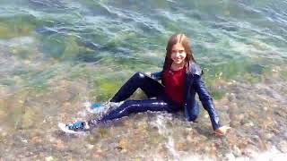 girl in wet jeans and a denim jacket gets wet in the water