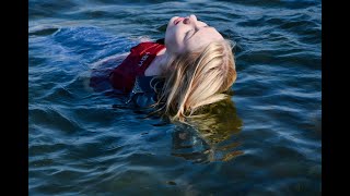 girl in wet clothes swims in the sea