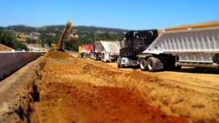 CAT 345 excavator loading out bottom dumps - shot in miniature mode