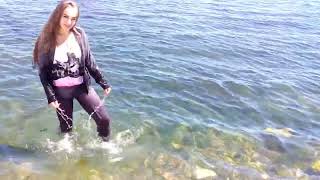 a girl in a tracksuit gets wet in the sea and swims