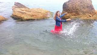 girl in a red dress gets wet in the sea