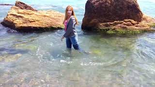 girl in wet clothes plays in the sea