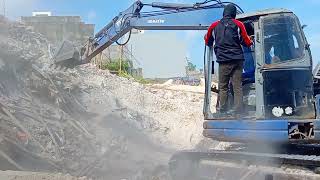 excavator kecil membersihkan puing puing bangunan .