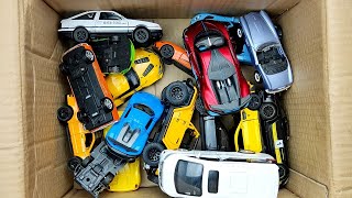 Box full of various miniature cars Peugeot, Jaguar, Pagani, Hyundai, Cadillac One, Opel, DHL