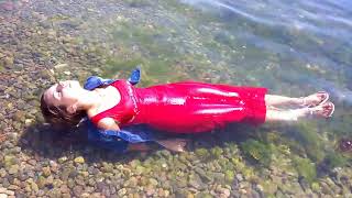 girl in a red dress gets wet in the sea