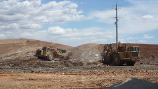 Caterpillar scrapers cutting for a new roadway section.