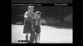 Older boy teaches younger boy to ride a too large bicycle.  Archive film 62952